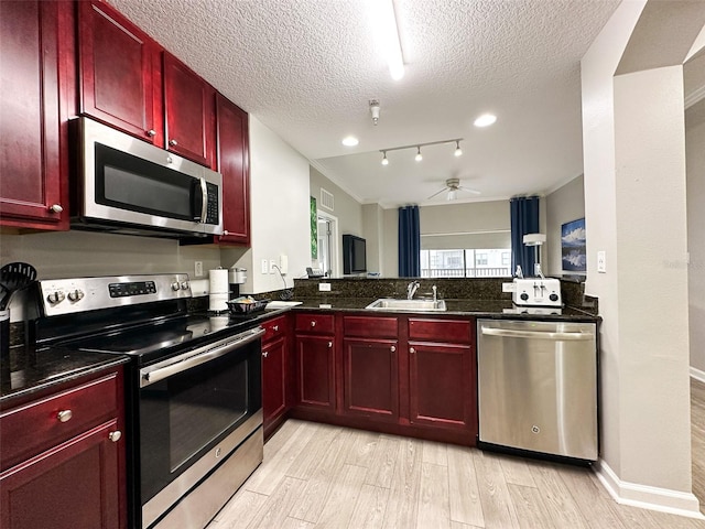 kitchen featuring kitchen peninsula, light wood-type flooring, appliances with stainless steel finishes, a textured ceiling, and ceiling fan