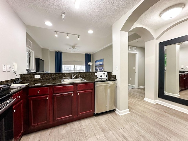 kitchen with light hardwood / wood-style flooring, stainless steel appliances, dark stone countertops, sink, and a textured ceiling