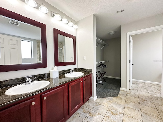 bathroom with walk in shower, vanity, a textured ceiling, and tile patterned floors