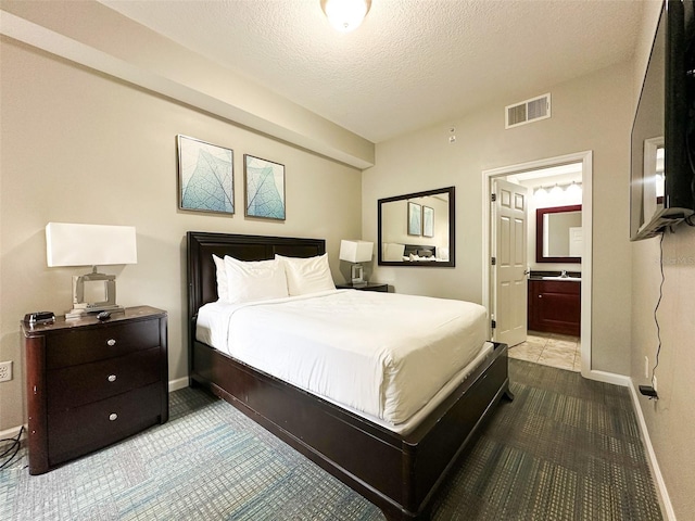 bedroom with a textured ceiling and ensuite bath