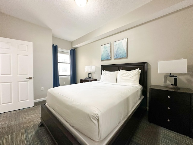 bedroom featuring a textured ceiling and dark colored carpet