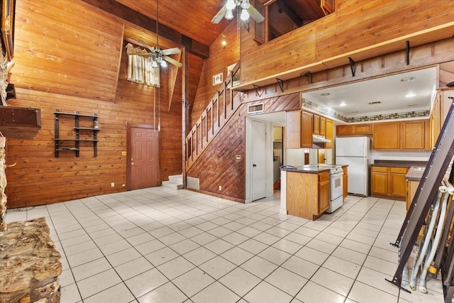 kitchen with white appliances, light tile patterned flooring, wooden walls, and a kitchen island