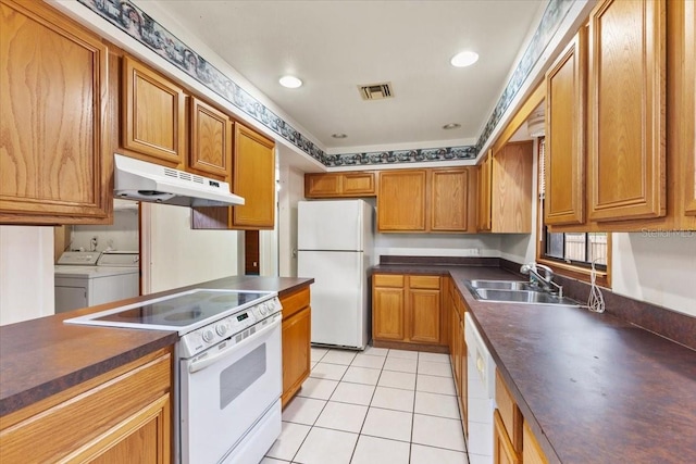 kitchen featuring sink, washing machine and dryer, white appliances, and light tile patterned floors