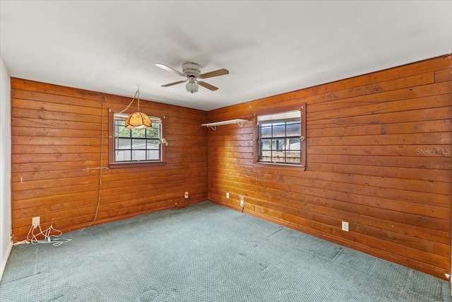 unfurnished room featuring wood walls, ceiling fan, and carpet floors