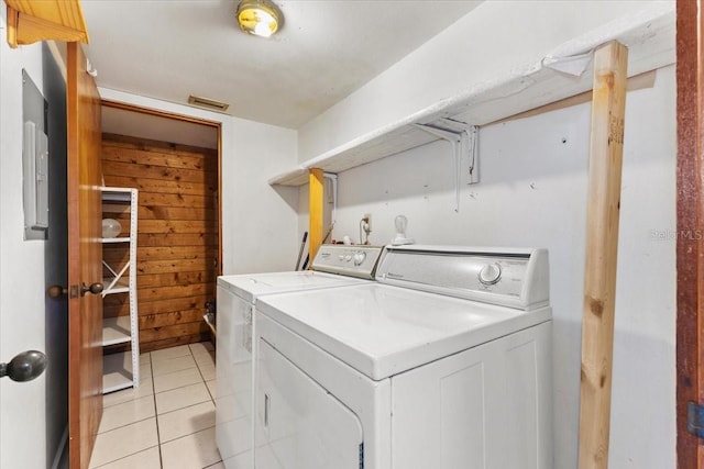 washroom featuring wooden walls, light tile patterned flooring, and separate washer and dryer