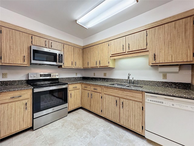 kitchen featuring sink, appliances with stainless steel finishes, and dark stone counters