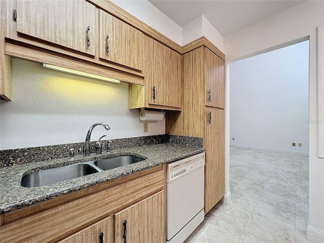 kitchen featuring white dishwasher, sink, and dark stone counters