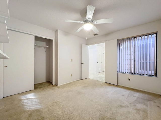 unfurnished bedroom featuring light carpet, a closet, and ceiling fan