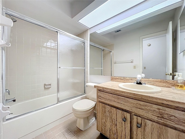 full bathroom featuring tile patterned floors, toilet, bath / shower combo with glass door, vanity, and a skylight