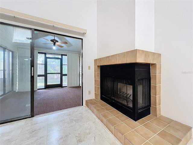 unfurnished living room featuring ceiling fan, carpet flooring, a high ceiling, and a tile fireplace