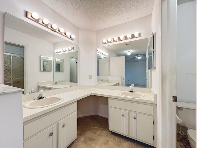 bathroom featuring vanity, a shower with shower door, a textured ceiling, and toilet