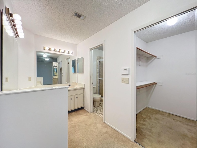 bathroom featuring vanity, a textured ceiling, toilet, and walk in shower