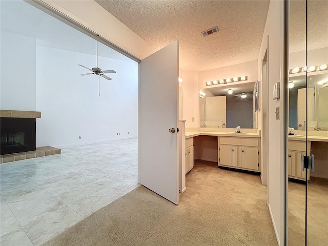 bathroom featuring vanity, a textured ceiling, and a tile fireplace