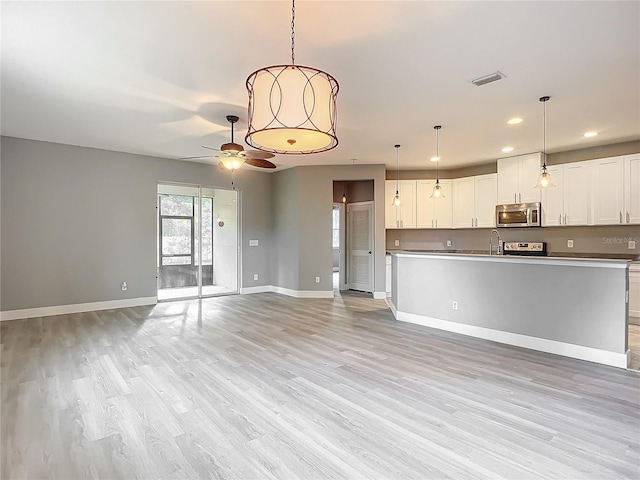 unfurnished living room with sink, ceiling fan, and light hardwood / wood-style flooring