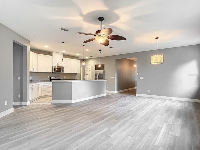 kitchen with a center island, appliances with stainless steel finishes, pendant lighting, and white cabinetry