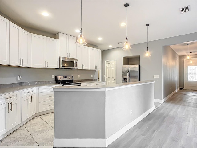 kitchen featuring appliances with stainless steel finishes, a center island, decorative light fixtures, and white cabinets