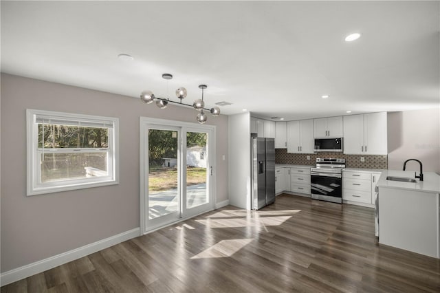 kitchen featuring stainless steel appliances, dark hardwood / wood-style flooring, pendant lighting, white cabinetry, and an inviting chandelier