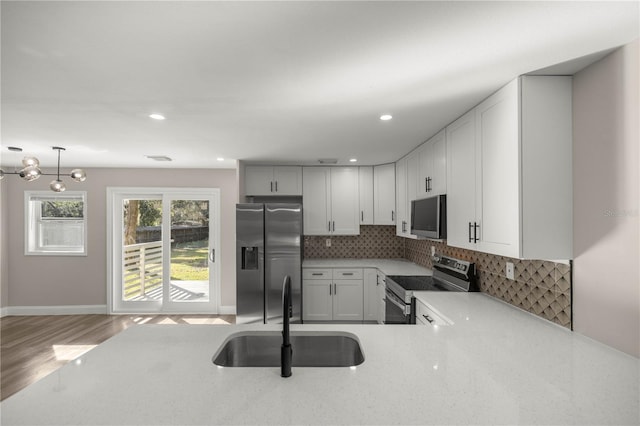 kitchen with decorative backsplash, pendant lighting, hardwood / wood-style floors, sink, and stainless steel appliances