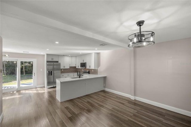 kitchen featuring dark hardwood / wood-style floors, white cabinets, sink, kitchen peninsula, and appliances with stainless steel finishes