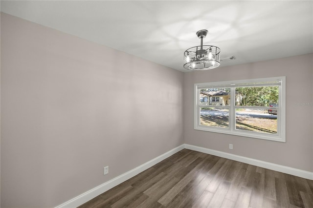 empty room featuring an inviting chandelier and dark hardwood / wood-style floors