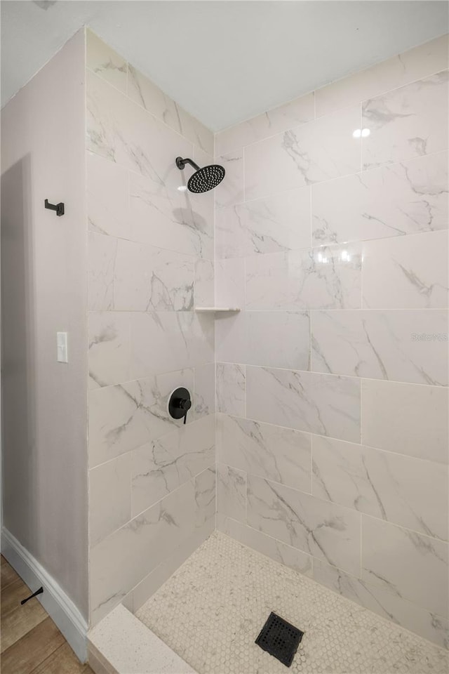 bathroom with wood-type flooring and tiled shower