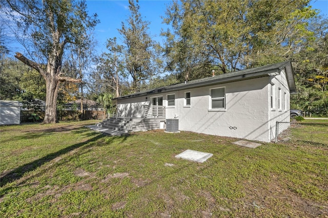 back of house featuring central AC unit and a yard