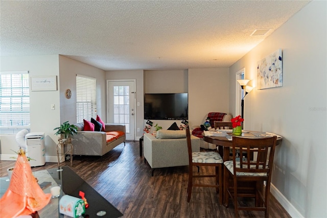 living room with a textured ceiling, plenty of natural light, and dark hardwood / wood-style floors