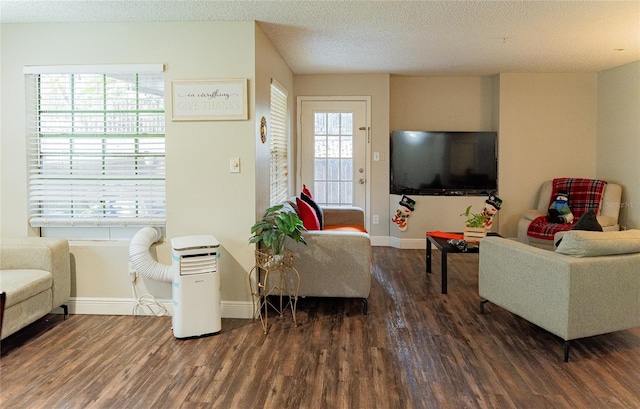 living room with a textured ceiling, dark hardwood / wood-style floors, and a healthy amount of sunlight