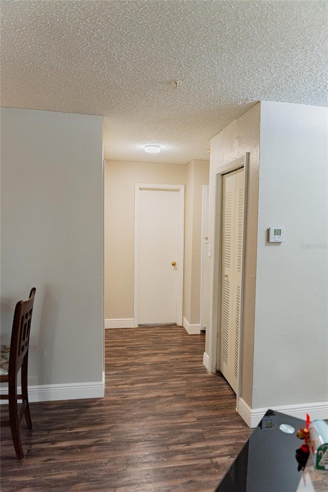 corridor with dark hardwood / wood-style floors and a textured ceiling