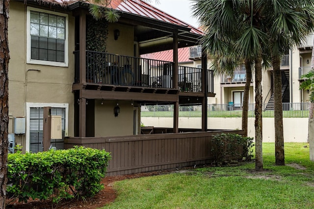 view of property exterior with a balcony and a lawn