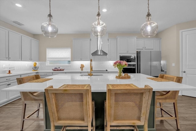 kitchen featuring stainless steel appliances, an island with sink, pendant lighting, and a breakfast bar area