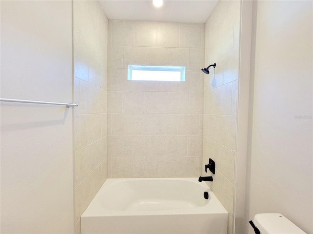 bathroom featuring toilet and tiled shower / bath