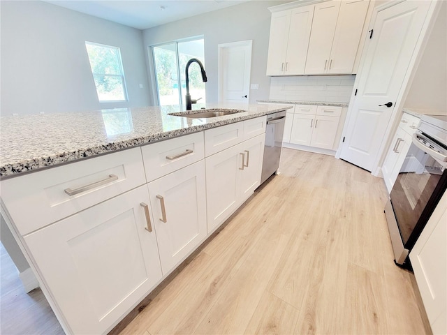 kitchen featuring light stone countertops, sink, white cabinetry, stainless steel appliances, and light hardwood / wood-style flooring