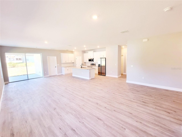 unfurnished living room featuring sink and light hardwood / wood-style flooring