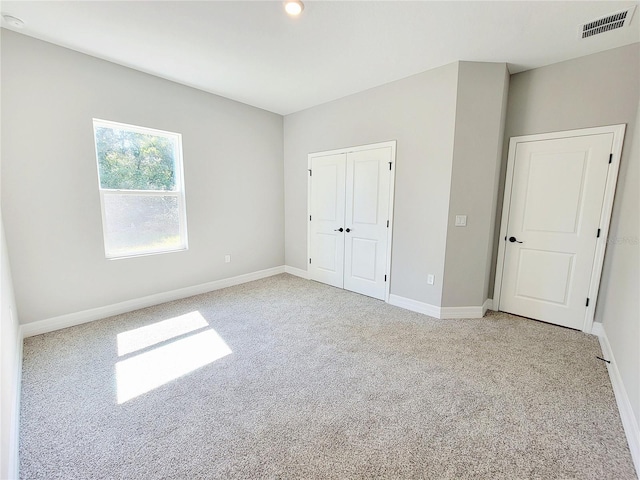 unfurnished bedroom featuring light carpet and a closet