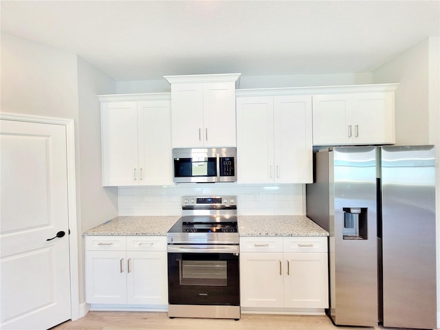 kitchen with light stone counters, stainless steel appliances, decorative backsplash, and white cabinets