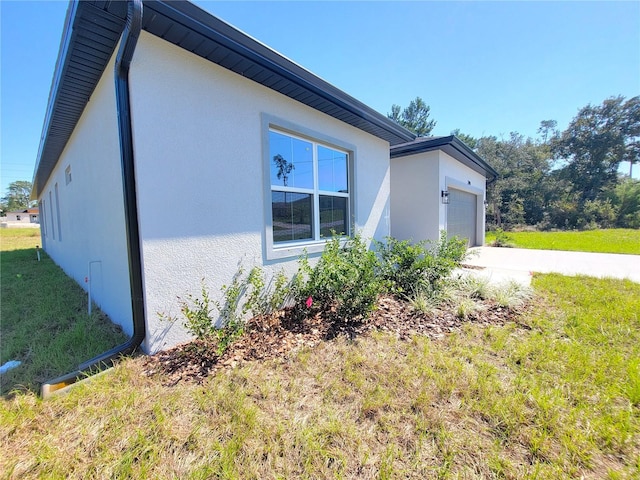 view of side of property featuring a garage and a lawn