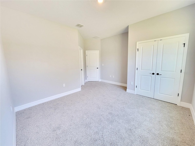 unfurnished bedroom featuring light carpet and a closet