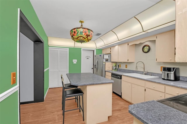 kitchen featuring a breakfast bar area, stainless steel appliances, sink, a center island, and light wood-type flooring