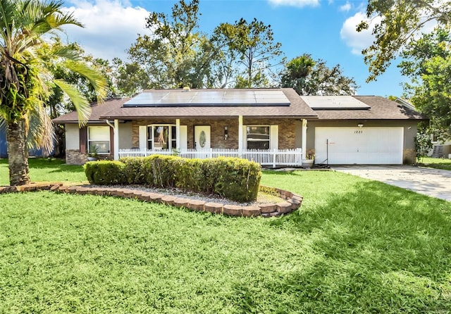 ranch-style home featuring covered porch, solar panels, a front lawn, and a garage