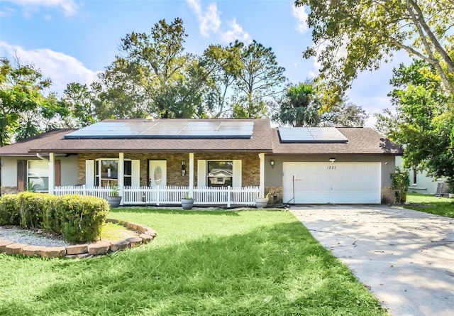 ranch-style home with solar panels, a front yard, covered porch, and a garage