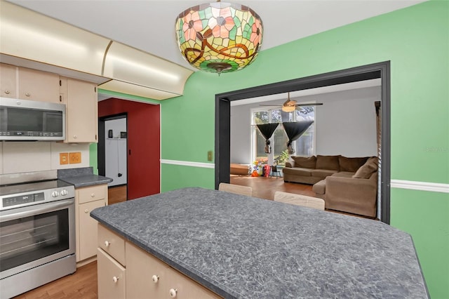 kitchen featuring appliances with stainless steel finishes, light hardwood / wood-style flooring, and ceiling fan