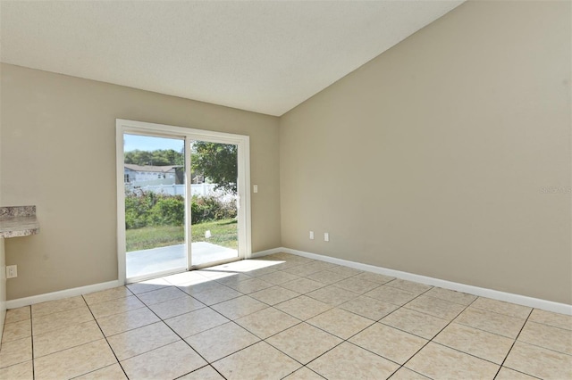 unfurnished room with a textured ceiling, lofted ceiling, and light tile patterned floors