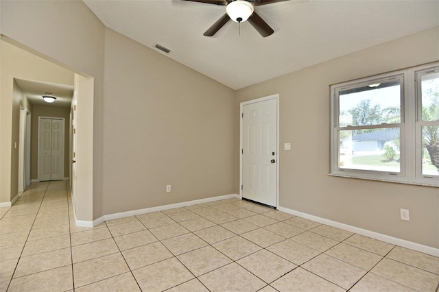 tiled spare room featuring lofted ceiling, ceiling fan, and a textured ceiling