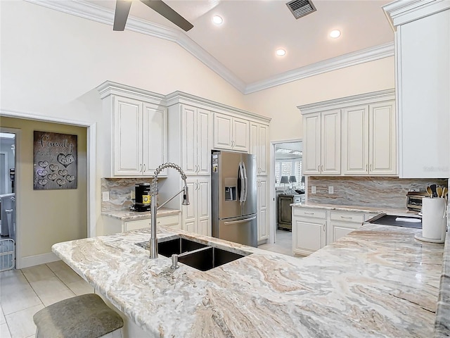 kitchen with sink, stainless steel fridge with ice dispenser, white cabinets, and vaulted ceiling