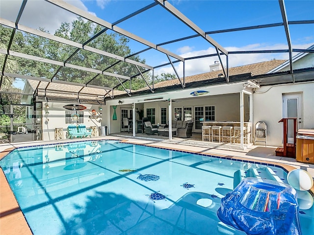 view of pool with outdoor lounge area, a patio, glass enclosure, and ceiling fan