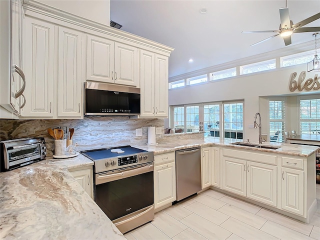 kitchen featuring kitchen peninsula, stainless steel appliances, sink, and a wealth of natural light