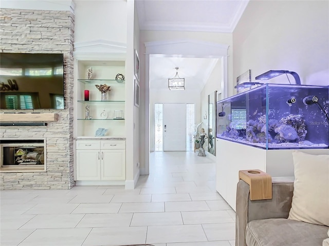 tiled entryway featuring a notable chandelier, crown molding, a stone fireplace, and high vaulted ceiling