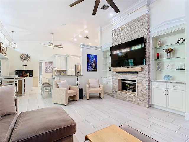 living room featuring a stone fireplace, lofted ceiling, built in features, and crown molding