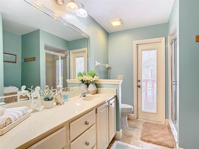 bathroom with a shower with door, vanity, toilet, and tile patterned floors